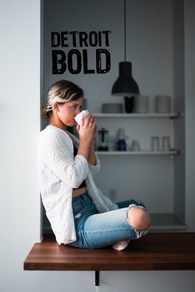 girl drinking the best coffee in the world detroit bold coffee strong coffee in background